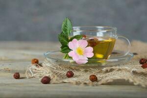 Rose hip on a cup plate with herbal tea. photo