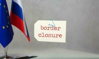 Border closure. written on a paper tag  is hanging in front of two flags -EU-Russia photo