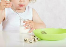 Small girl eats natural sugar free yogurt. Closeup photo