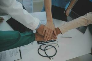 multirracial médico equipo teniendo un reunión con doctores en blanco laboratorio abrigos y quirúrgico matorrales sentado a un mesa que se discute un pacientes registros foto