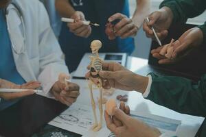 multirracial médico equipo teniendo un reunión con doctores en blanco laboratorio abrigos y quirúrgico matorrales sentado a un mesa que se discute un pacientes registros foto