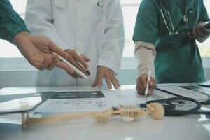 multirracial médico equipo teniendo un reunión con doctores en blanco laboratorio abrigos y quirúrgico matorrales sentado a un mesa que se discute un pacientes registros foto