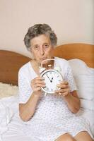 Old woman with vintage alarm clock photo