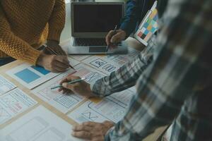 Close up ux developer and ui designer brainstorming about mobile app interface wireframe design on table with customer breif and color code at modern office.Creative digital development agency photo
