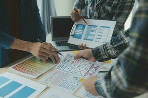 Close up ux developer and ui designer brainstorming about mobile app interface wireframe design on table with customer breif and color code at modern office.Creative digital development agency photo