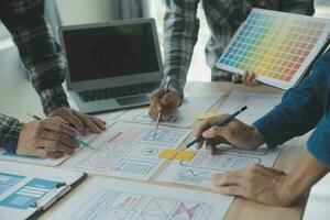 Close up ux developer and ui designer brainstorming about mobile app interface wireframe design on table with customer breif and color code at modern office.Creative digital development agency photo