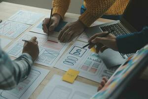 Close up ux developer and ui designer brainstorming about mobile app interface wireframe design on table with customer breif and color code at modern office.Creative digital development agency photo