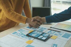 Close up ux developer and ui designer brainstorming about mobile app interface wireframe design on table with customer breif and color code at modern office.Creative digital development agency photo