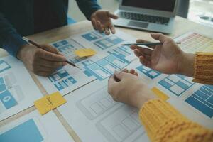 Close up ux developer and ui designer brainstorming about mobile app interface wireframe design on table with customer breif and color code at modern office.Creative digital development agency photo