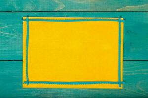 Yellow felt fabric on a cyan wooden surface. Background photo