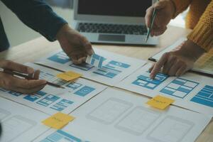 Close up ux developer and ui designer brainstorming about mobile app interface wireframe design on table with customer breif and color code at modern office.Creative digital development agency photo
