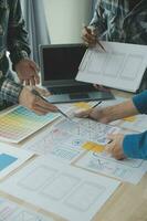 Close up ux developer and ui designer brainstorming about mobile app interface wireframe design on table with customer breif and color code at modern office.Creative digital development agency photo