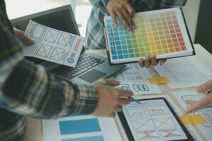 Close up ux developer and ui designer brainstorming about mobile app interface wireframe design on table with customer breif and color code at modern office.Creative digital development agency photo