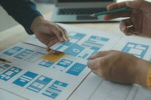 Close up ux developer and ui designer brainstorming about mobile app interface wireframe design on table with customer breif and color code at modern office.Creative digital development agency photo