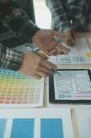 Close up ux developer and ui designer brainstorming about mobile app interface wireframe design on table with customer breif and color code at modern office.Creative digital development agency photo