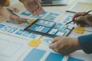 Close up ux developer and ui designer brainstorming about mobile app interface wireframe design on table with customer breif and color code at modern office.Creative digital development agency photo