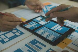 Close up ux developer and ui designer brainstorming about mobile app interface wireframe design on table with customer breif and color code at modern office.Creative digital development agency photo