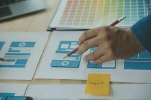 Close up ux developer and ui designer brainstorming about mobile app interface wireframe design on table with customer breif and color code at modern office.Creative digital development agency photo