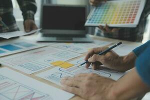 Close up ux developer and ui designer brainstorming about mobile app interface wireframe design on table with customer breif and color code at modern office.Creative digital development agency photo