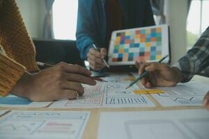 Close up ux developer and ui designer brainstorming about mobile app interface wireframe design on table with customer breif and color code at modern office.Creative digital development agency photo