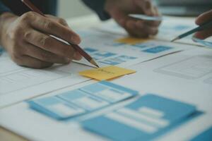 Close up ux developer and ui designer brainstorming about mobile app interface wireframe design on table with customer breif and color code at modern office.Creative digital development agency photo