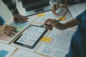 Close up ux developer and ui designer brainstorming about mobile app interface wireframe design on table with customer breif and color code at modern office.Creative digital development agency photo