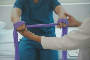 Doctor or Physiotherapist working examining treating injured arm of athlete male patient, stretching and exercise, Doing the Rehabilitation therapy pain in clinic. photo