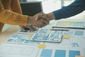 Close up ux developer and ui designer brainstorming about mobile app interface wireframe design on table with customer breif and color code at modern office.Creative digital development agency photo