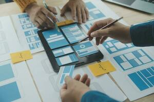 Close up ux developer and ui designer brainstorming about mobile app interface wireframe design on table with customer breif and color code at modern office.Creative digital development agency photo