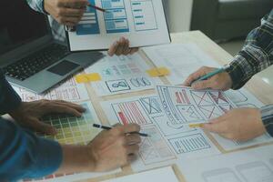 Close up ux developer and ui designer brainstorming about mobile app interface wireframe design on table with customer breif and color code at modern office.Creative digital development agency photo