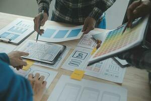 Close up ux developer and ui designer brainstorming about mobile app interface wireframe design on table with customer breif and color code at modern office.Creative digital development agency photo