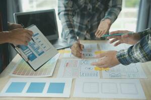Close up ux developer and ui designer brainstorming about mobile app interface wireframe design on table with customer breif and color code at modern office.Creative digital development agency photo