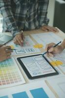 Close up ux developer and ui designer brainstorming about mobile app interface wireframe design on table with customer breif and color code at modern office.Creative digital development agency photo