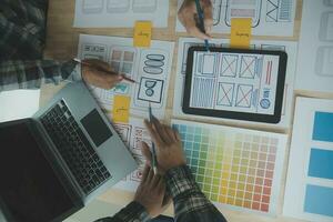 Close up ux developer and ui designer brainstorming about mobile app interface wireframe design on table with customer breif and color code at modern office.Creative digital development agency photo