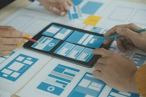 Close up ux developer and ui designer brainstorming about mobile app interface wireframe design on table with customer breif and color code at modern office.Creative digital development agency photo