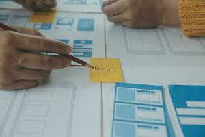 Close up ux developer and ui designer brainstorming about mobile app interface wireframe design on table with customer breif and color code at modern office.Creative digital development agency photo