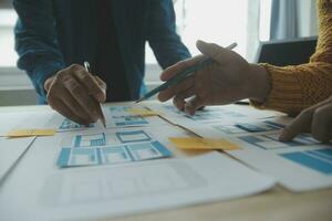 Close up ux developer and ui designer brainstorming about mobile app interface wireframe design on table with customer breif and color code at modern office.Creative digital development agency photo