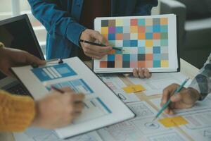 Close up ux developer and ui designer brainstorming about mobile app interface wireframe design on table with customer breif and color code at modern office.Creative digital development agency photo