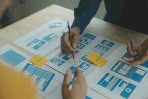 Close up ux developer and ui designer brainstorming about mobile app interface wireframe design on table with customer breif and color code at modern office.Creative digital development agency photo