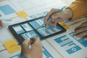 Close up ux developer and ui designer brainstorming about mobile app interface wireframe design on table with customer breif and color code at modern office.Creative digital development agency photo