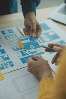 Close up ux developer and ui designer brainstorming about mobile app interface wireframe design on table with customer breif and color code at modern office.Creative digital development agency photo