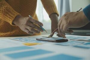 Close up ux developer and ui designer brainstorming about mobile app interface wireframe design on table with customer breif and color code at modern office.Creative digital development agency photo