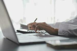Asian Business woman using calculator and laptop for doing math finance on an office desk, tax, report, accounting, statistics, and analytical research concept photo