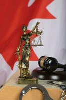 Statue of Themis and judge's gavel on a book. Flag of Canada in the background. photo