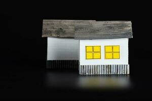 Two small paper houses on a black surface. photo