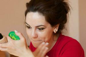 Young lady is applying make up on her face. Closeup photo