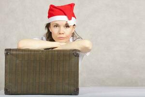 Young lady in Santa Claus hat and old suitcase photo