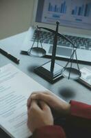 Justice and law concept.Male judge in a courtroom with the gavel, working with, computer and docking keyboard, eyeglasses, on table in morning light photo