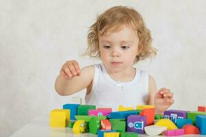 Girl builds up something from colourful geometrical figures and shapes. Closeup photo