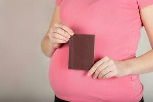 Young pregnant woman keeps her travel pass. Closeup photo